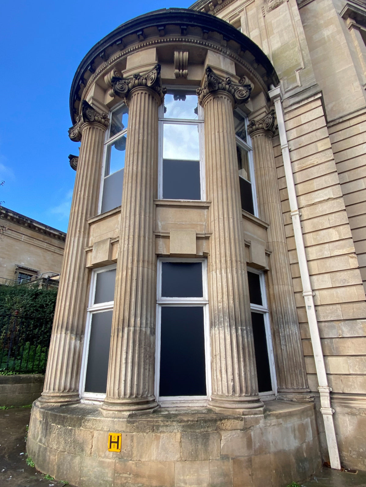 External view of windows in an older building, with blackout window film applied to the glass to block the view from both sides.