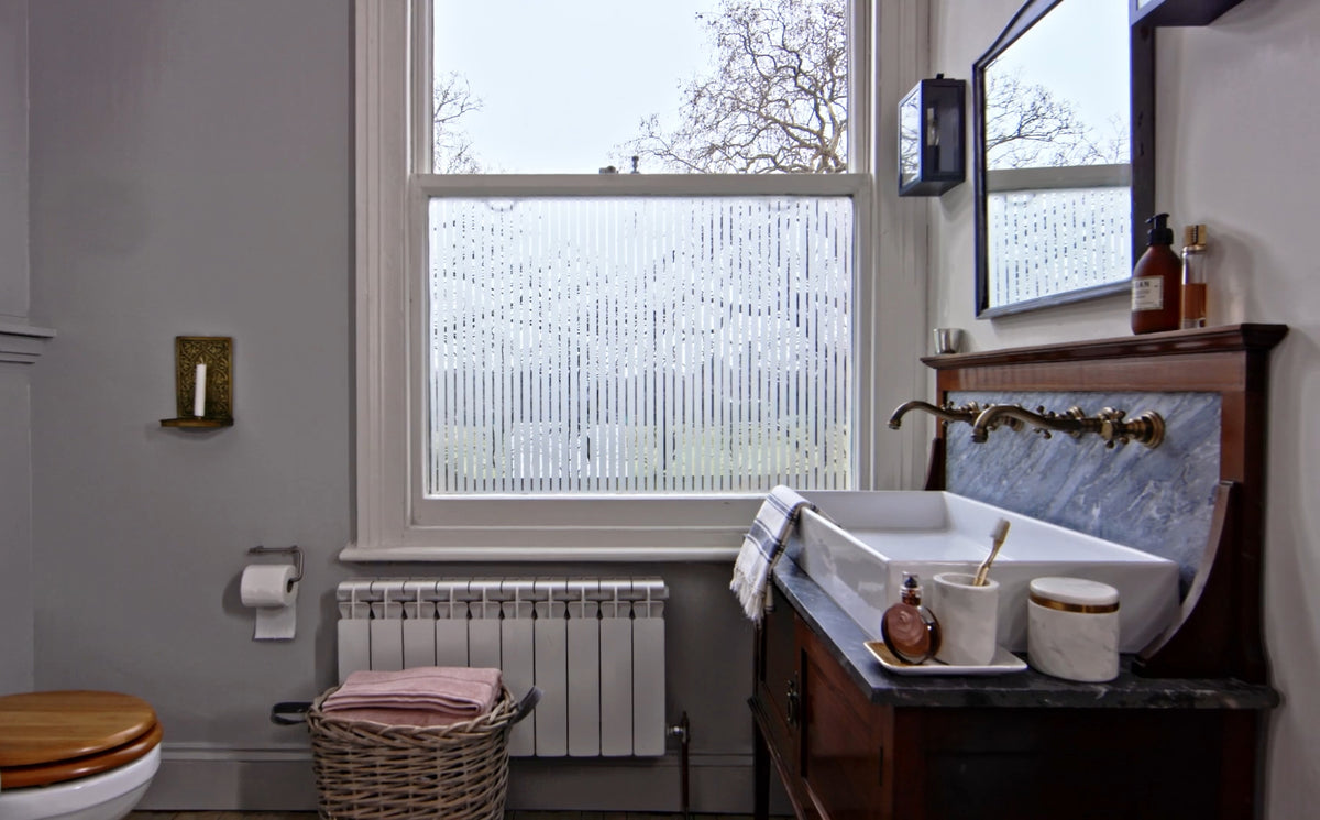 Stylish bathroom with a large window, featuring a geometric frosted window film pattern known as FB017 by The Window Film Company.