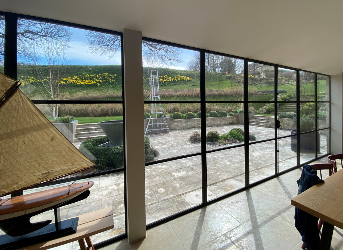 A modern interior with a large expanse of glazing overlooking a garden. The glazing has been fitted with glare reduction window film. 