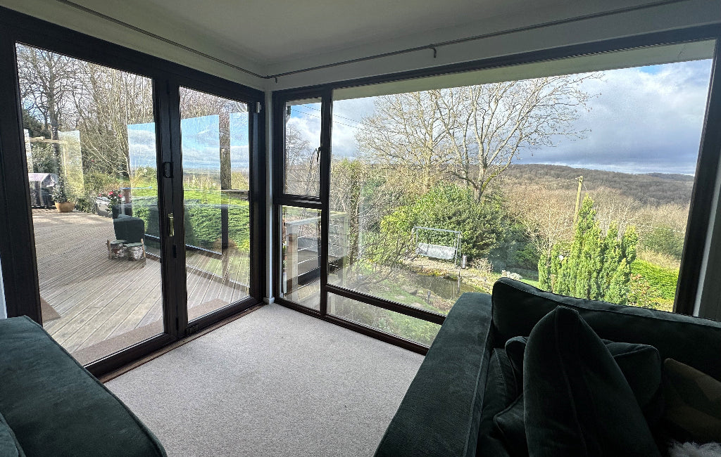 Internal view of a modern living room with large windows giving a view out over a large garden. The windows have glare reduction window film applied.