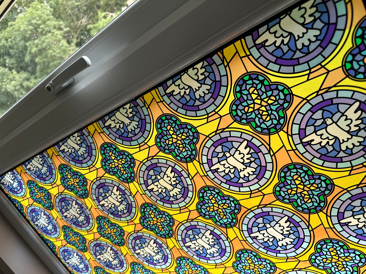 A close up of a window in a house, with a stained glass effect window film applied for decoration and two way privacy.