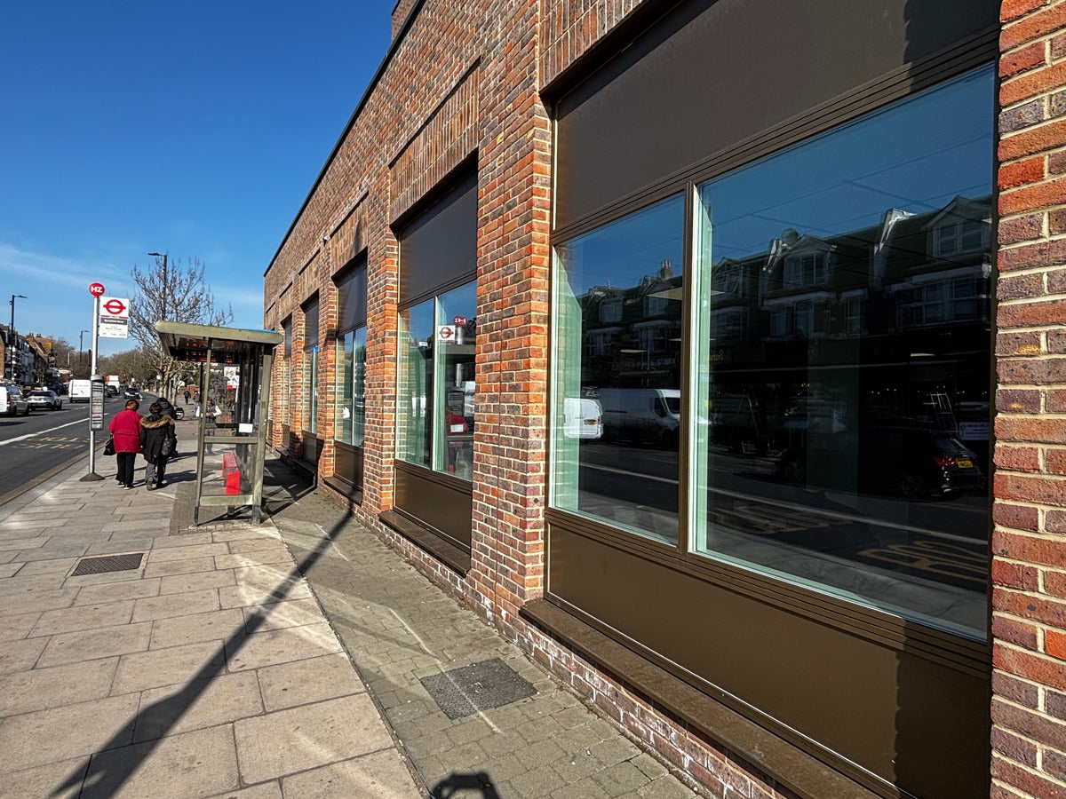 Brick building with large windows on a street corner, the glazing has anti-graffiti window film applied to it, to protect it from damage. 