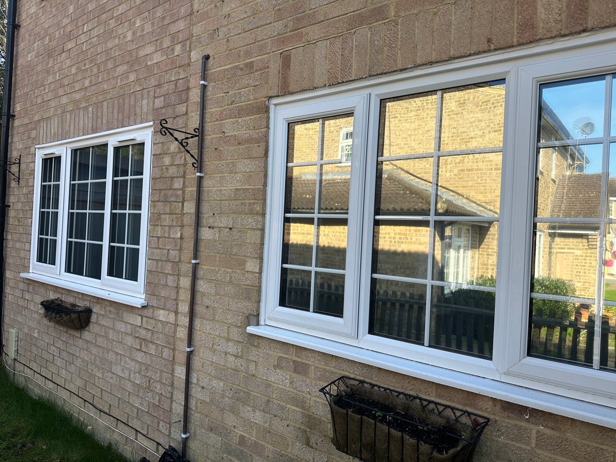 Brick wall with white-framed windows that have had anti-graffiti window film applied to them.