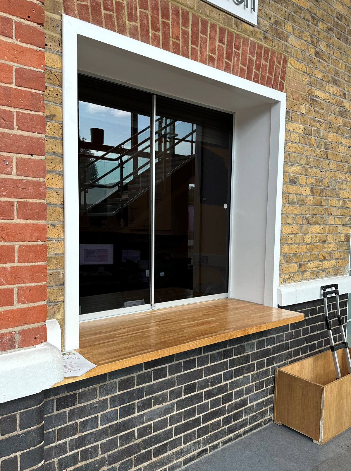 Window set in a brick wall with a wooden sill, featuring Black Pearl tinted window film for glare reduction. 