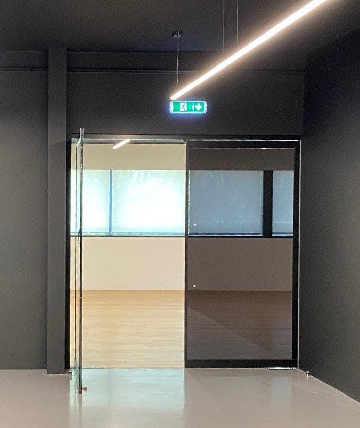 Doorway with glass doors, the panel on the right has Black pearl tinted glare reduction window film applied. 