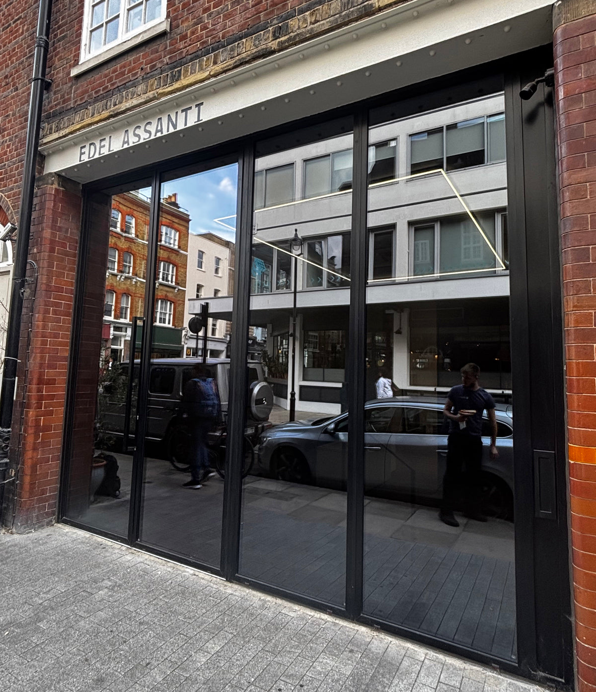 A shopfront with four large glass panels, each of which has had tinted glare reduction window film applied, delivering a stylish dark appearance. 