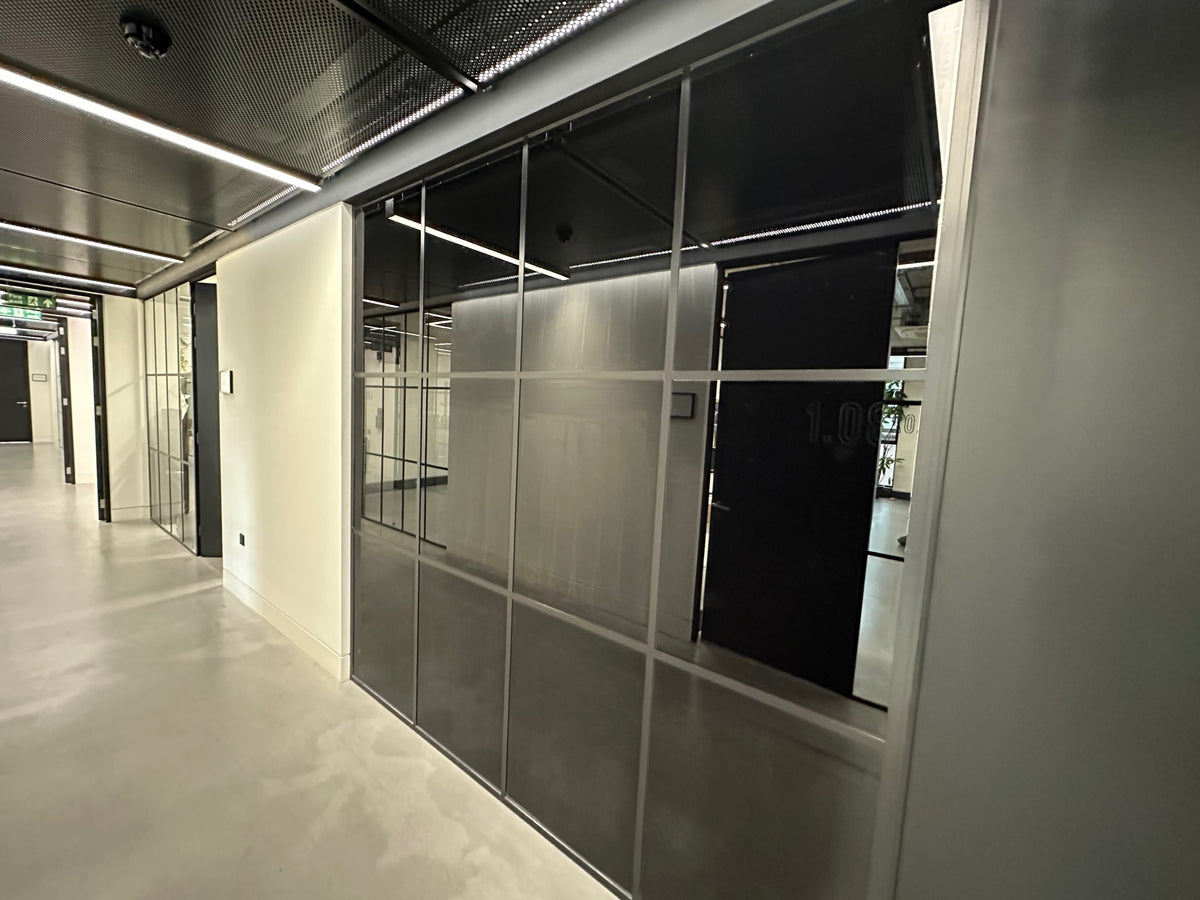 Internal view of a glass partition in a modern office setting, the glass has blackout privacy window film applied to block the view form both sides of the glazing. 