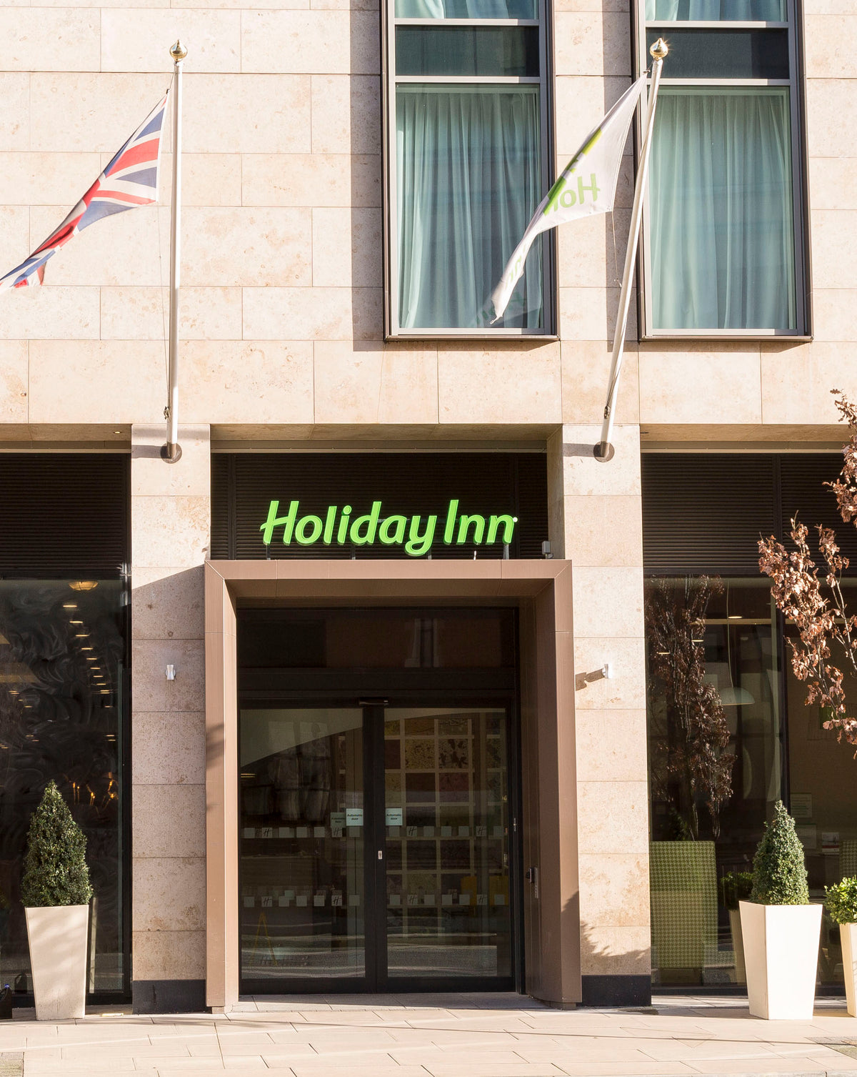 Holiday Inn entrance with flags and Clearplex clear safety film applied to the glass facade