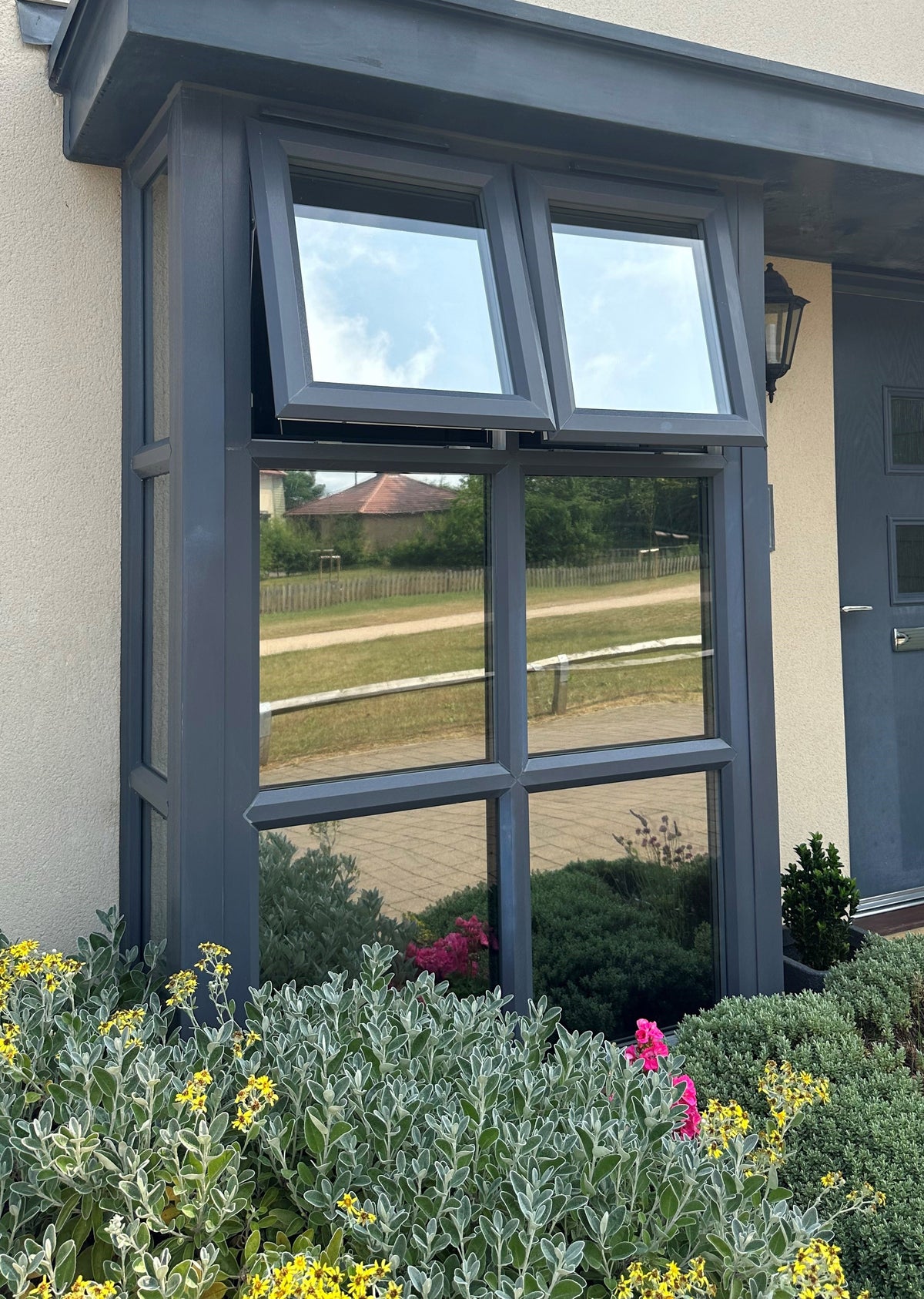 Close up view of a window at the front of a house, with Climate 35 heat reduction window film installed to the glass.