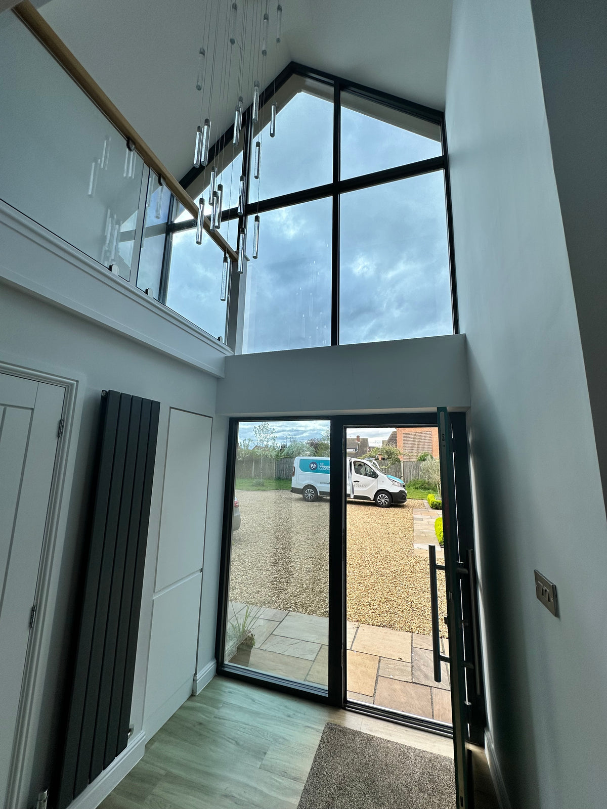 Interior view of a home with large glass windows with Climate 35 heat reduction window film installed and a van from The Window Film Company visible through the glass. 