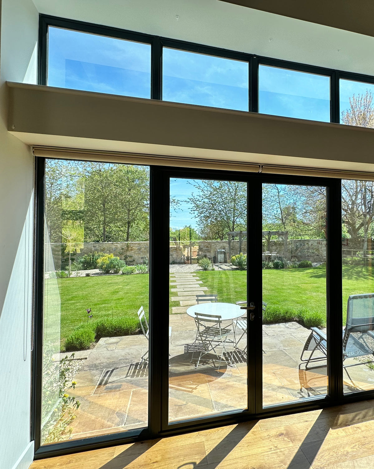 Patio doors and large glass windows facing a garden, with Climate 50 heat reduction window film applied to the glazing.