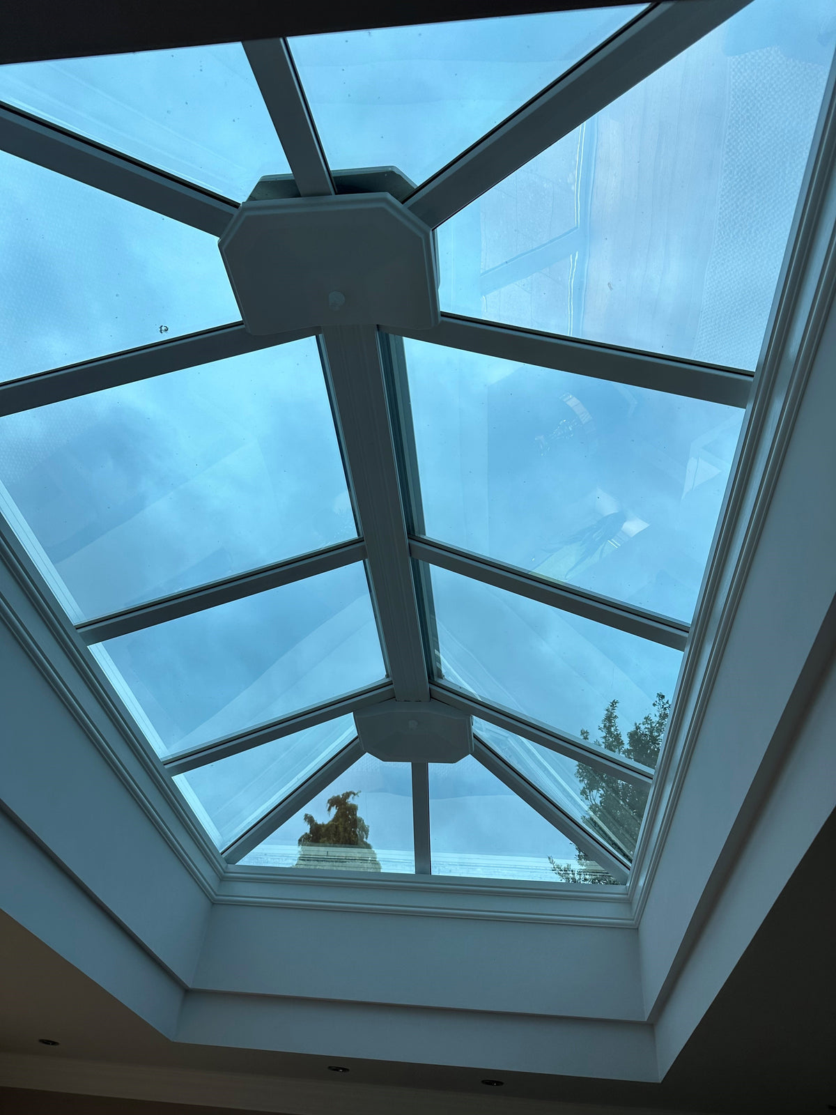 An internal view of a large glass skylight with a view of the sky and solar control window film applied to the internal side of the glazing. 