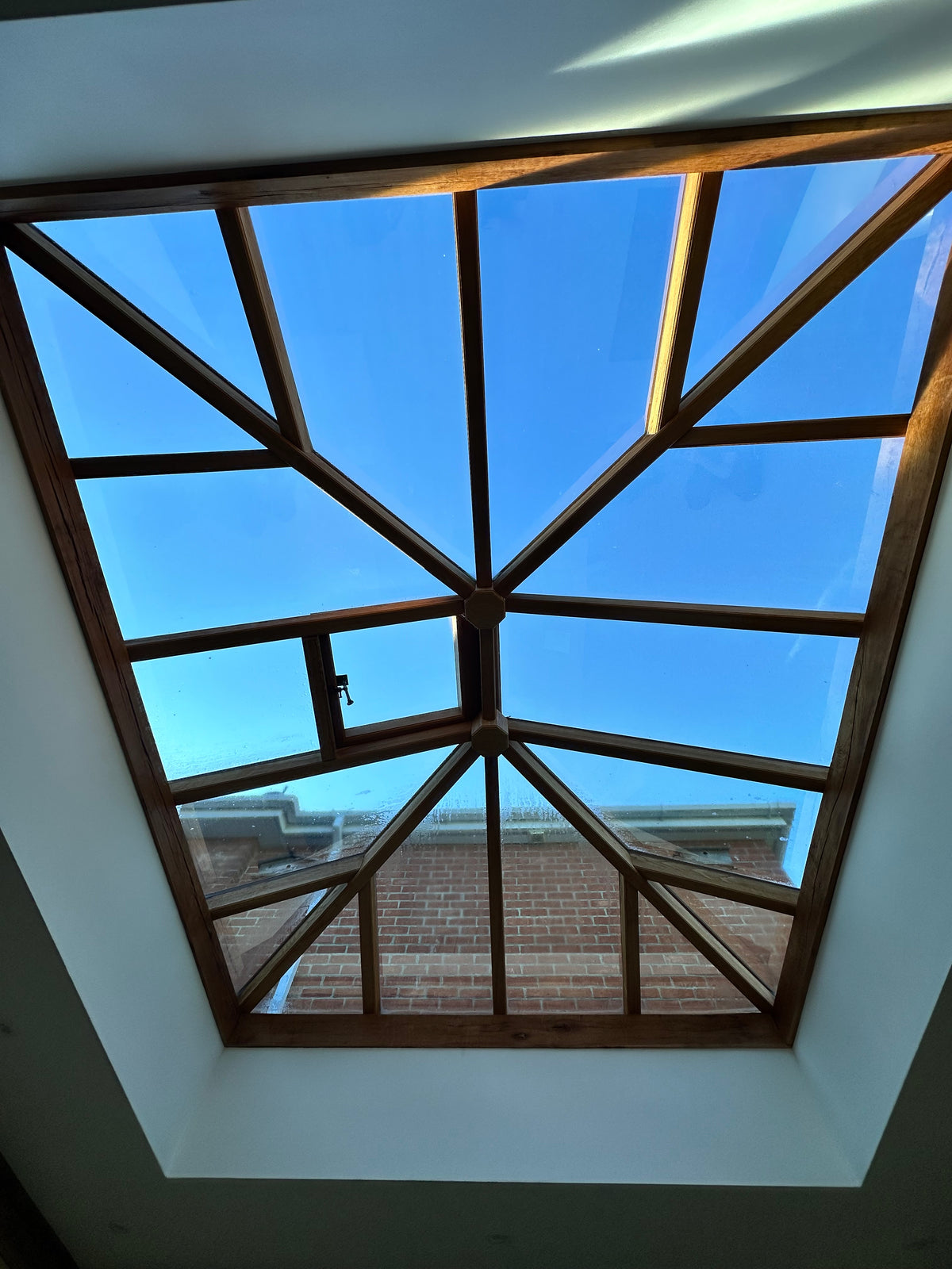 A large rooflight comprising several panes with heat and glare reduction window film applied, with a view of a bright blue sky through the glass. 