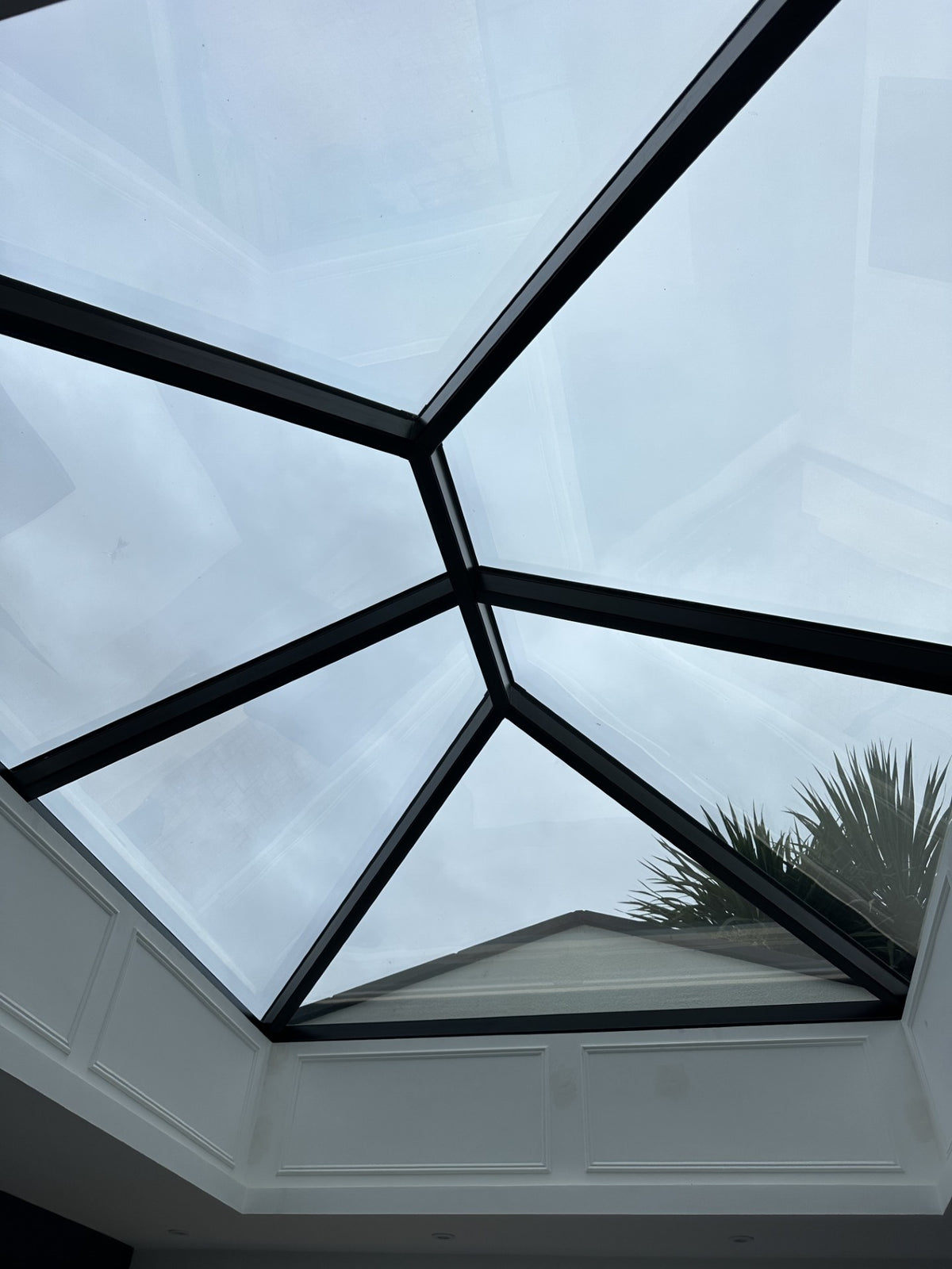 Skylight with glass panels and black frames in a residential setting, with solar control window film applied to the internal face of the glass. 