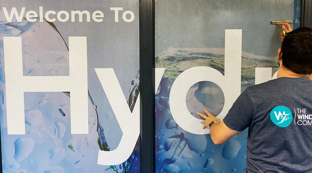 An installer from The Window Film Company fitting printed Contra Vision window film to an internal glass partition