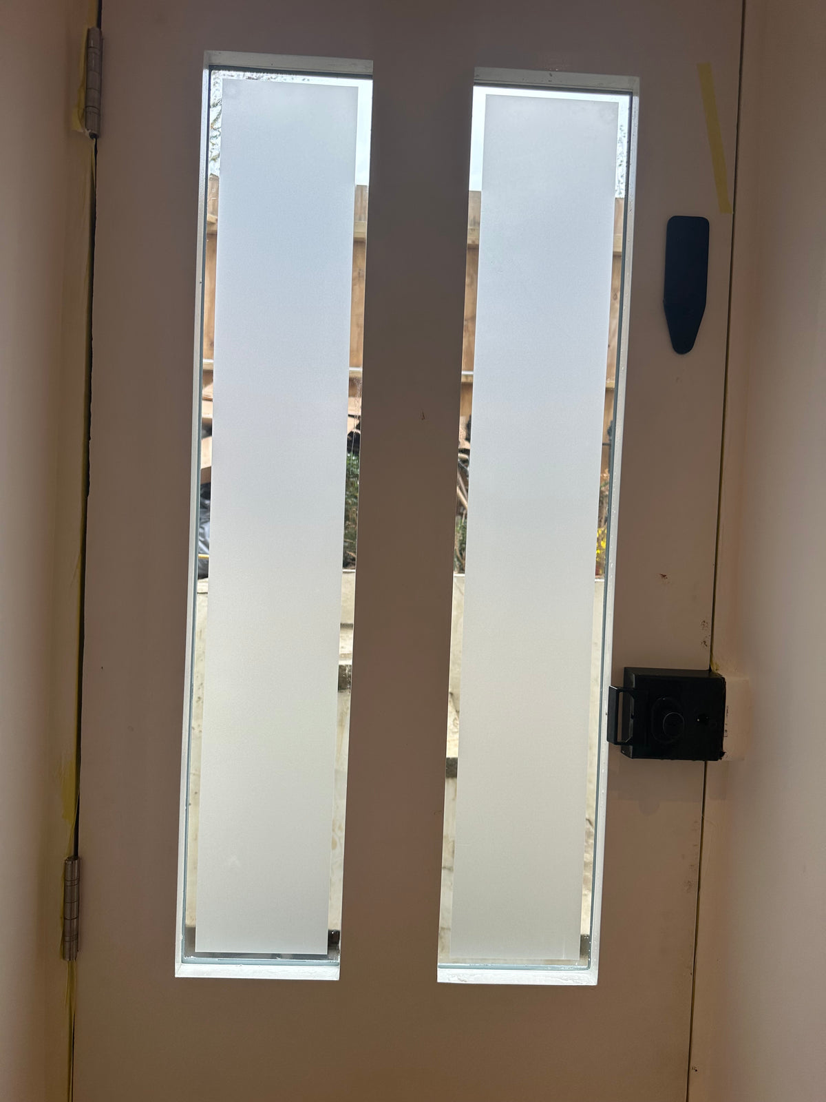 A door with two long rectangular glass panes within it, with frosted window film applied to the two glazed sections to deliver privacy.