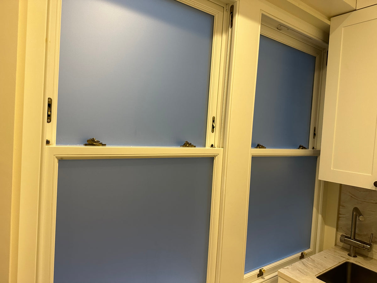 Kitchen window with four panes, with frosted window film applied to each panel, giving the glazing the appearance of frosted glass and blocking the view from both sides.