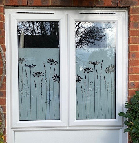 External view of a White double-glazed window with floral design window film applied to the glass. 