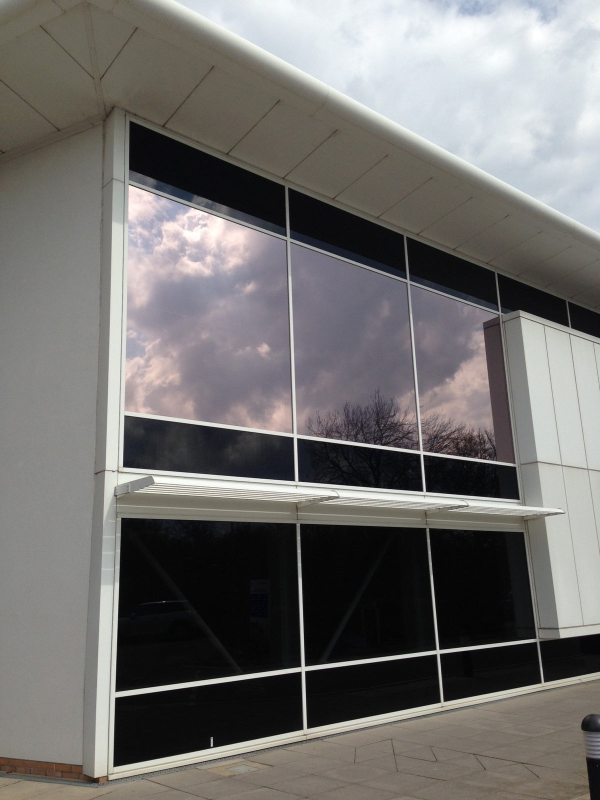 Modern building facade with large glass windows featuring solar bronze window film, delivering a sleek and stylish finish. 
