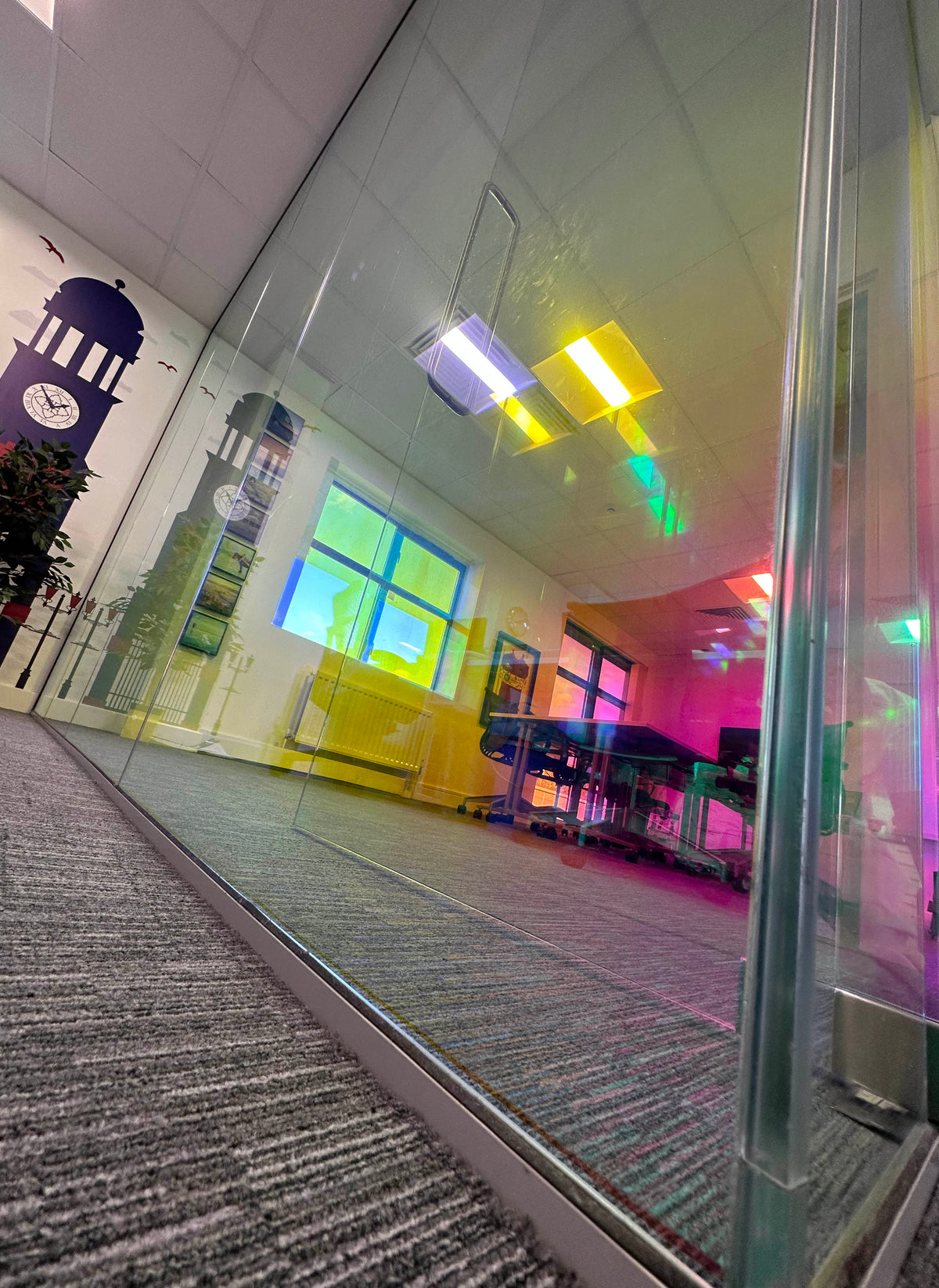 Colour change window film applied to glass partition in an office, giving a large glass partition the appearance of dichroic glass.