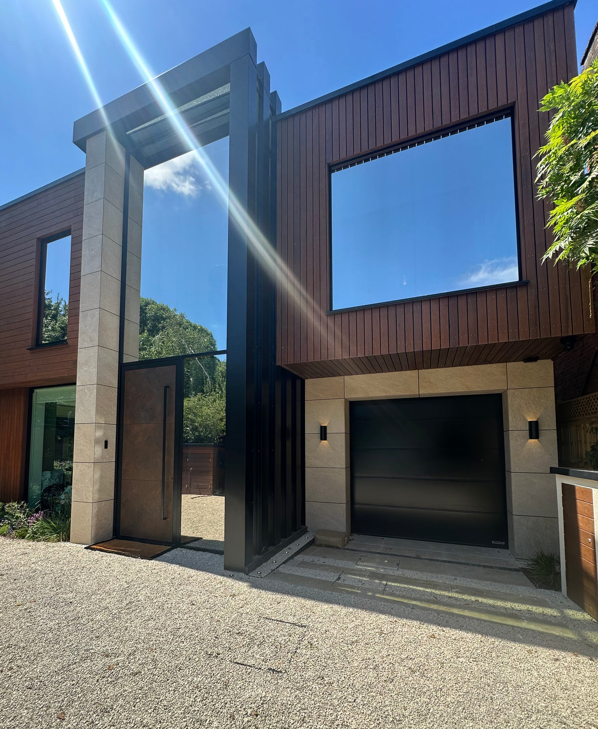 Exterior view of a modern house with reflective silver solar control window film applied to the large panels of glass. 