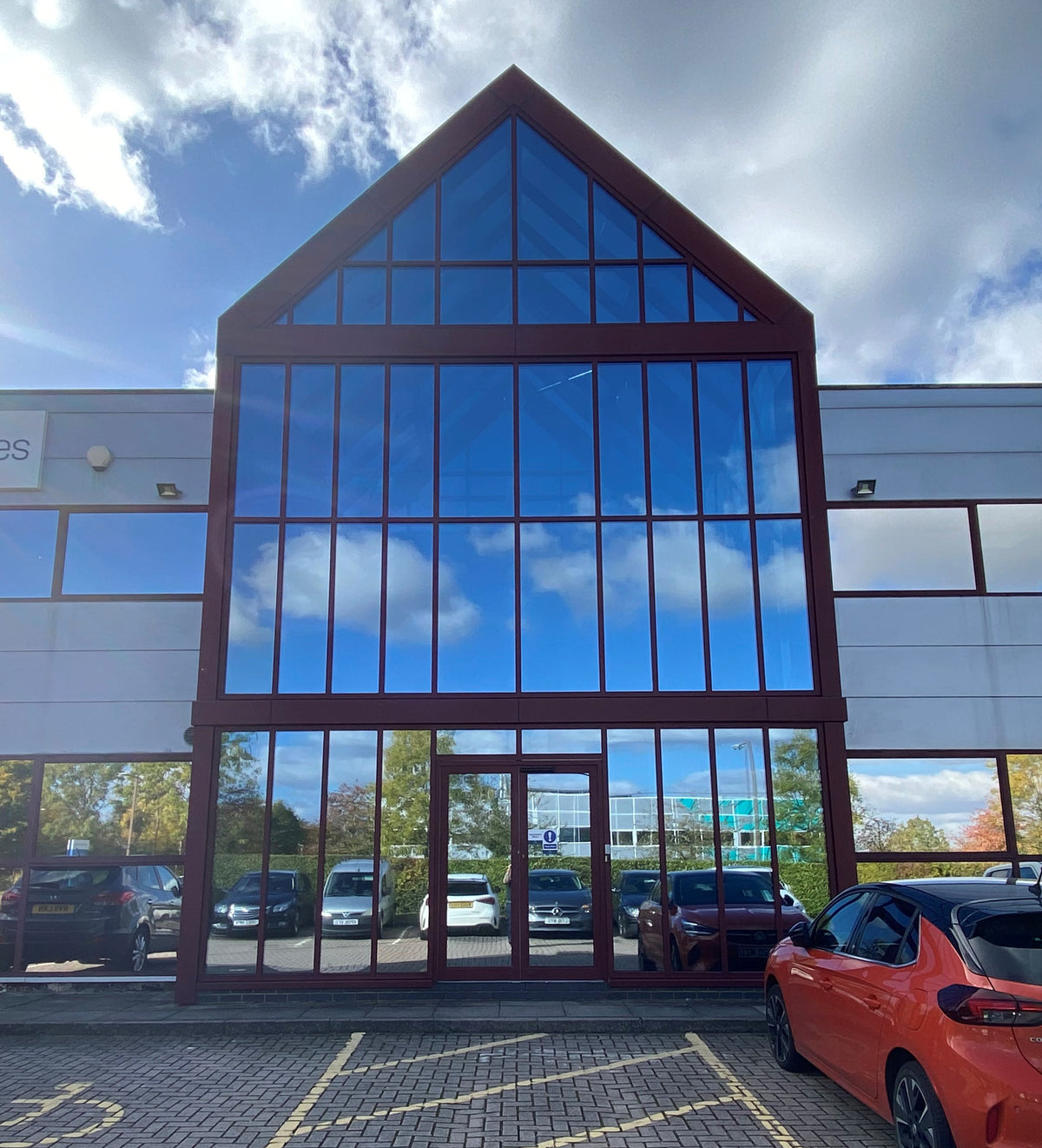 External view of a modern office building with a glass frontage. External grade solar control window film has been applied to the glass, giving it a silver, mirrored appearance.