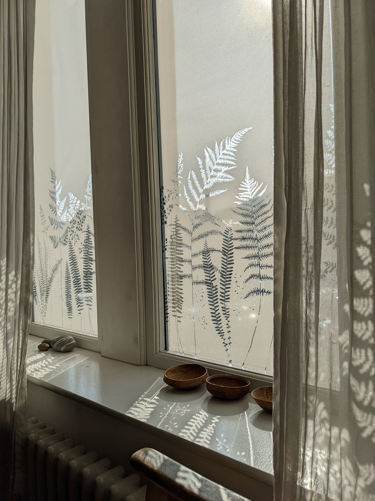 A large window with a frosted window film that has a nature theme print.