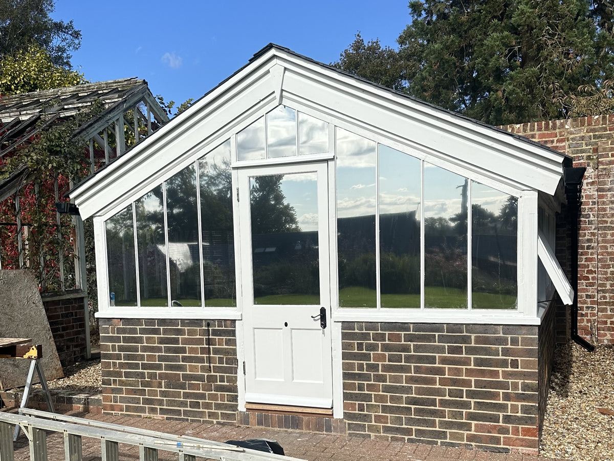 Looking a a small garden room style greenhouse that has had a mirrored window film applied to the glazed gable end.