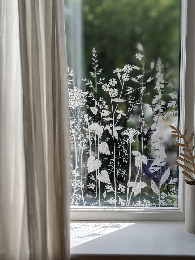 A window with a frosted patterned window film applied, featuring a floral inspired design. 