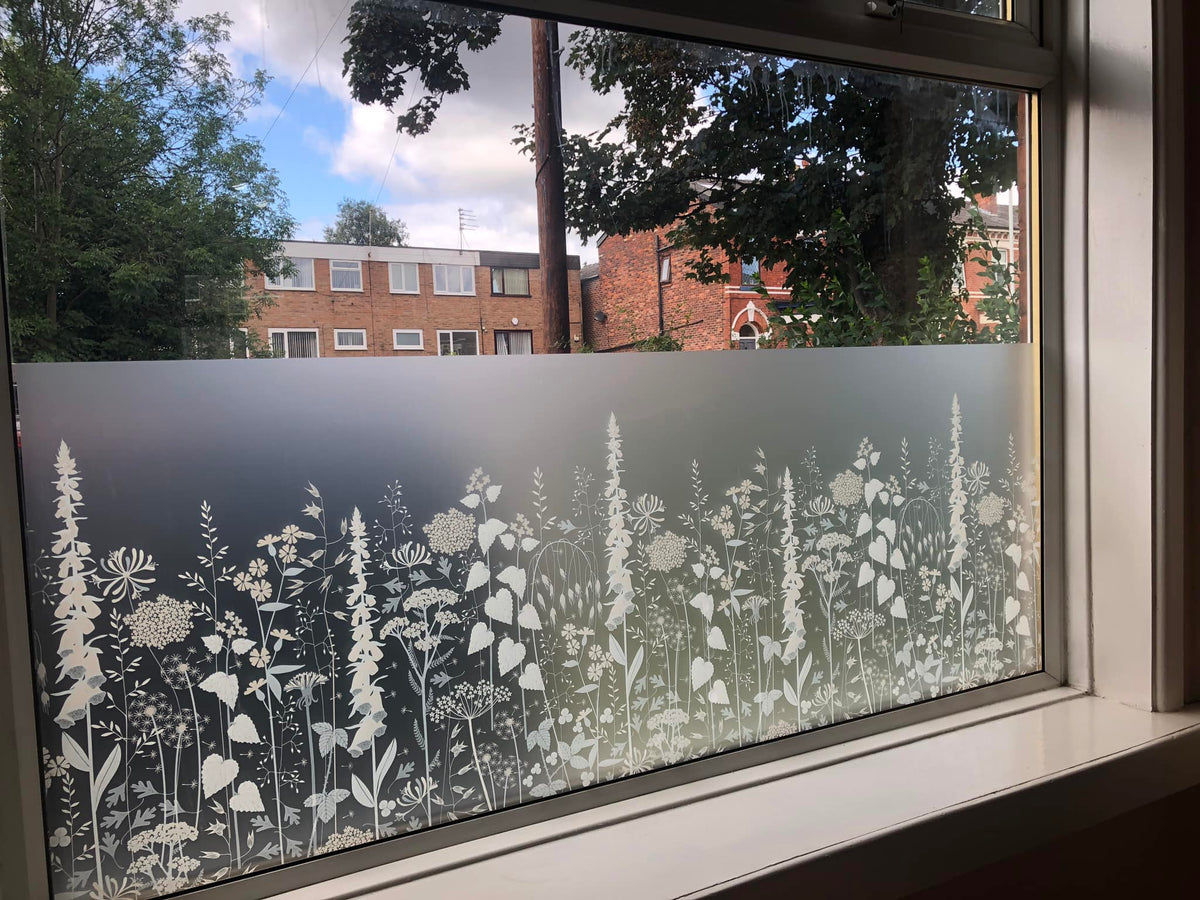 Window that has window film applied to the lower half of the pane. The film is frosted with a white printed pattern, providing privacy, while a view to the outside is possible through the unfilmed part of the glass.