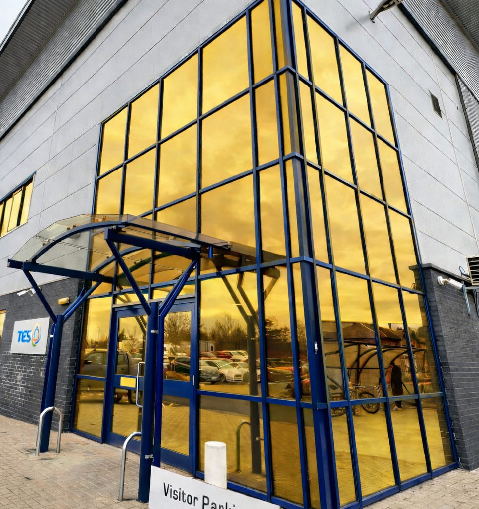 The glazed exterior of a building featuring vibrant reflective gold reflective window film applied to the glass panels.