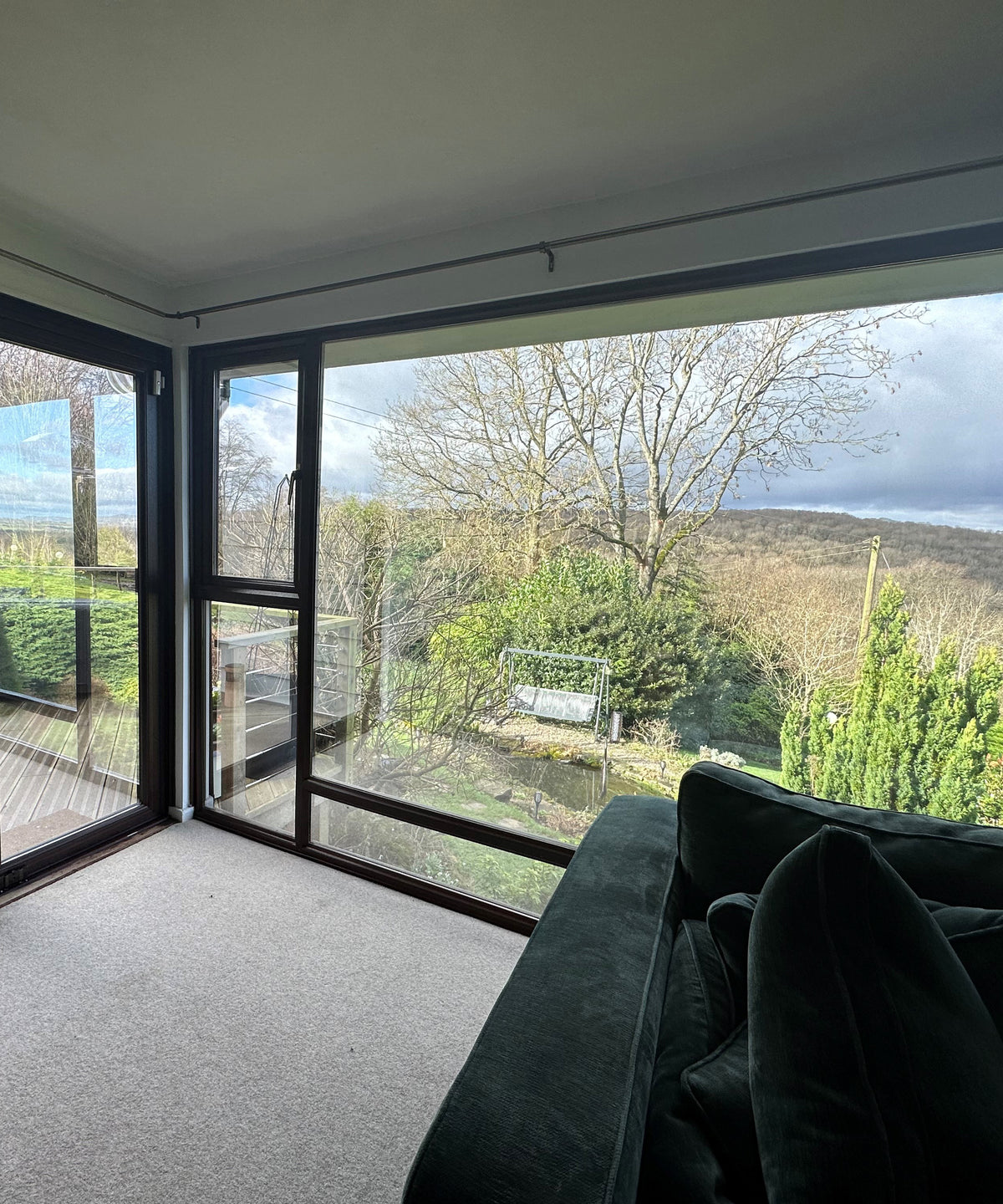 An internal view of a residential property with large glass windows. The windows have solar control window film applied to them, with a view out over countryside.