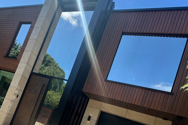 Modern house exterior with large windows that have a mirrored window film applied to reduce heat and glare.