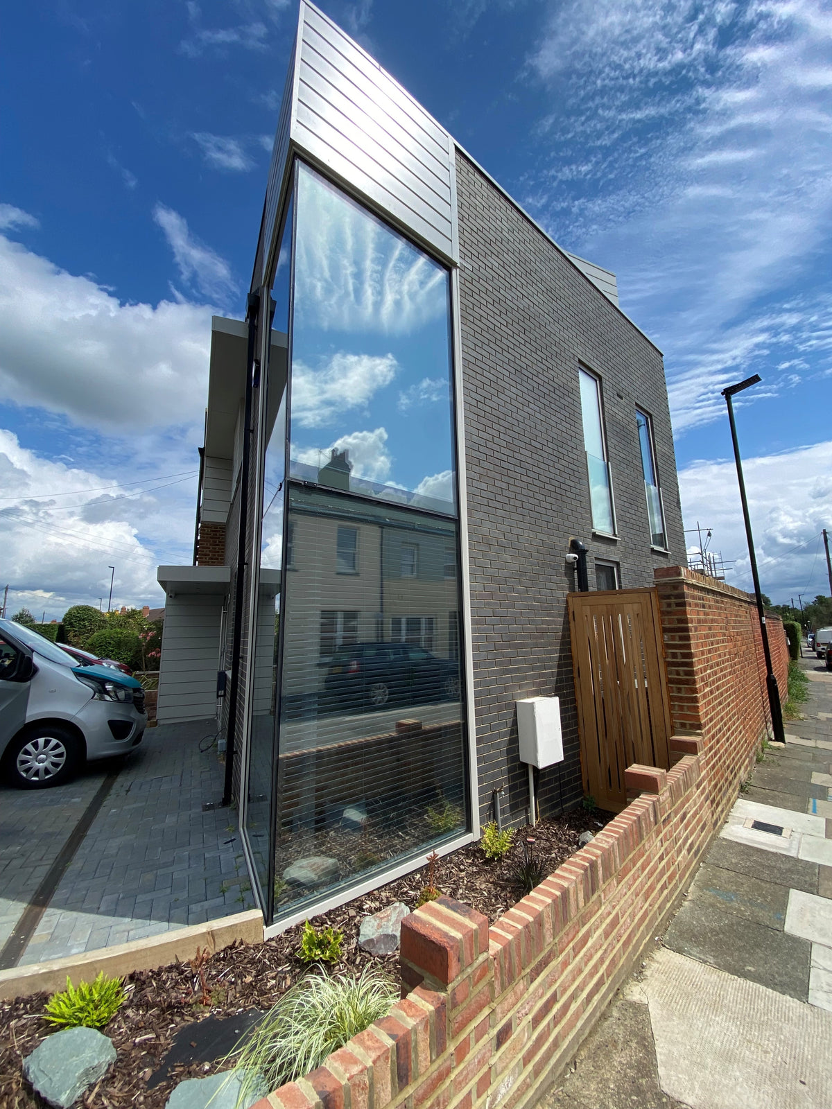 Modern house with large glass facade which has had a medium reflective silver solar control window film applied.