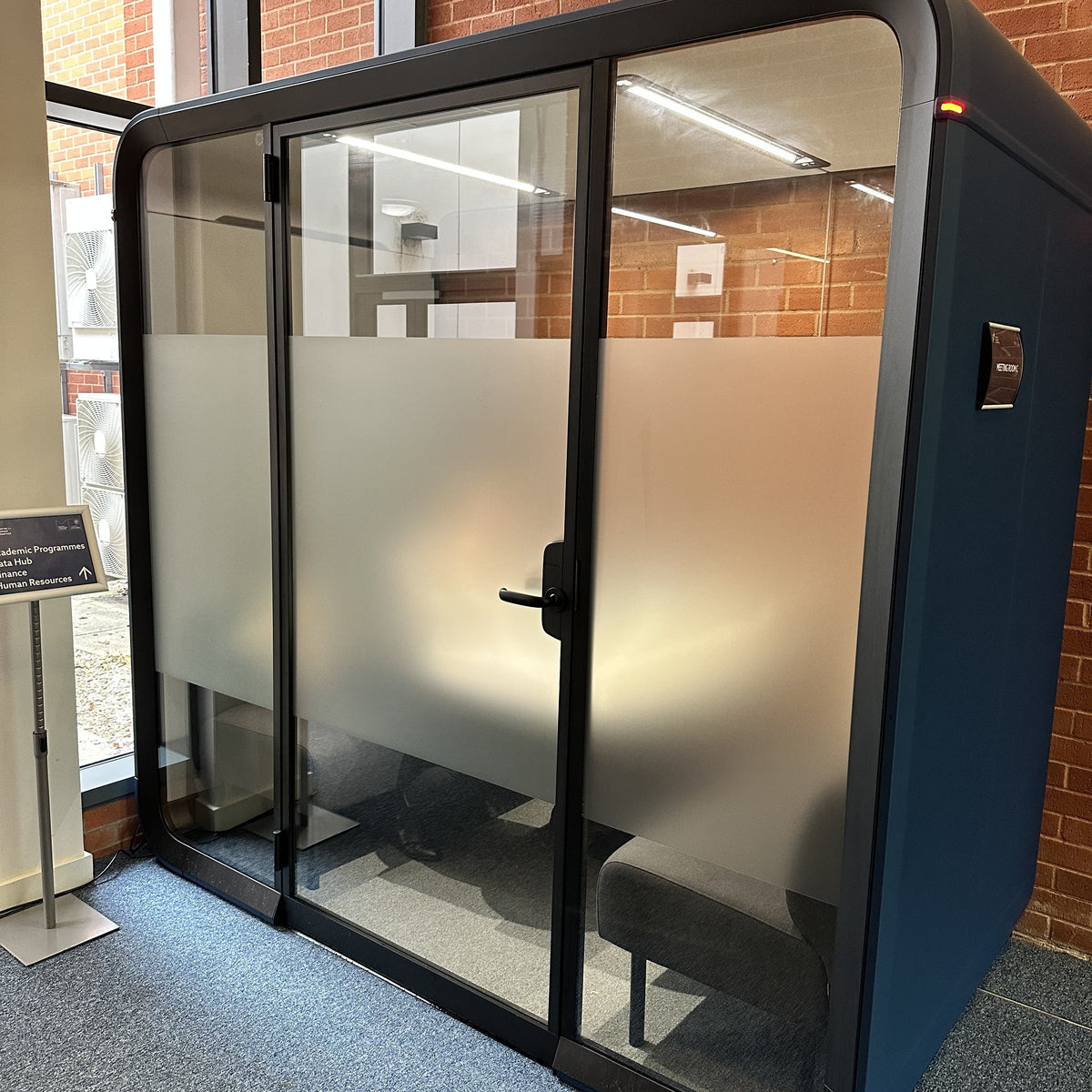 Modern office phone booth with glass walls and frosted window film applied for privacy.