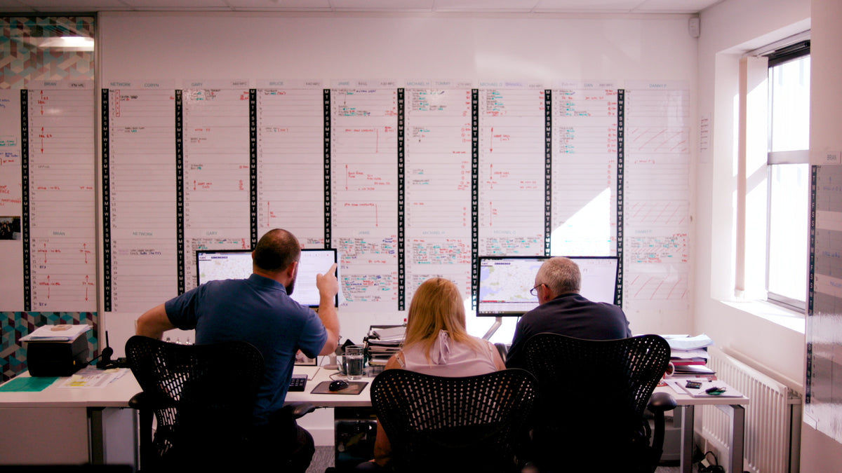 Three team members working at The Window Film Company's head office in Chesham, Buckinghamshire. The colleagues are working in front of computer screens and other detailed plans.