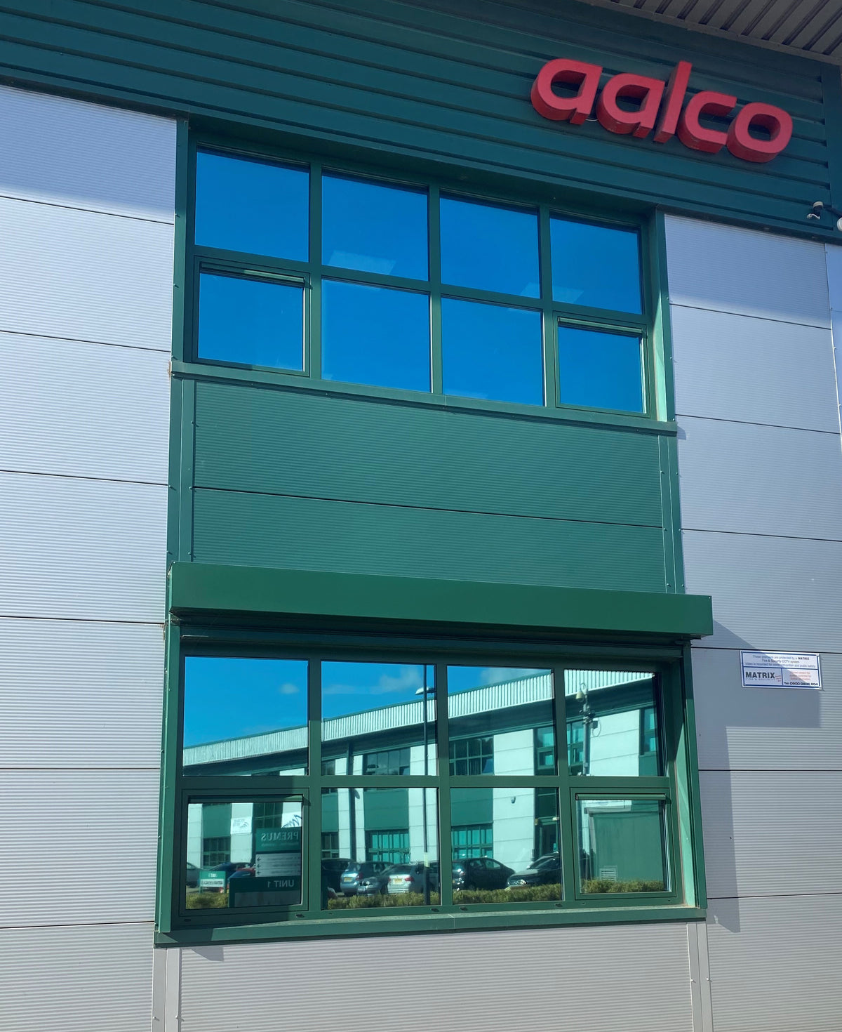 Building facade featuring two sets of windows, with solar control window film applied, delivering a reflective appearance to reduce heat and glare.