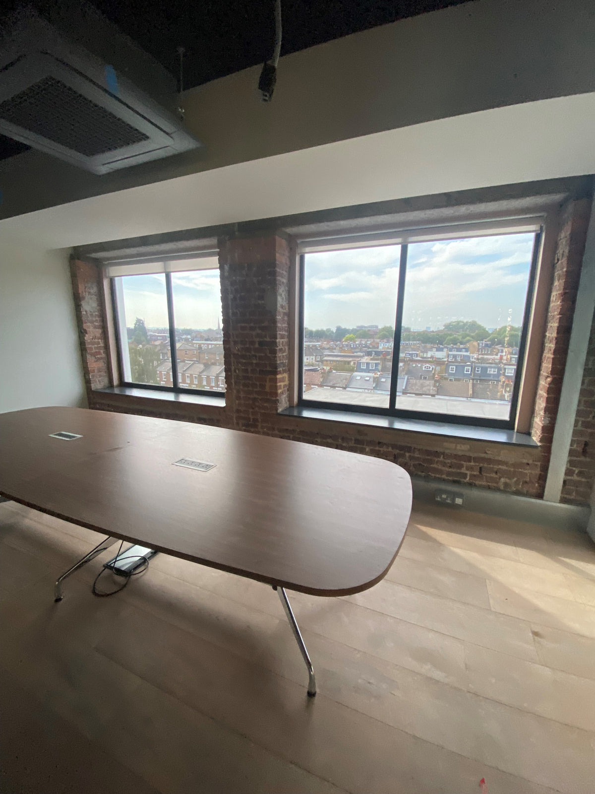 Internal shot of a conference room with large windows that have Optiview solar control film applied. The view is maintained, showing a view over a residential area.