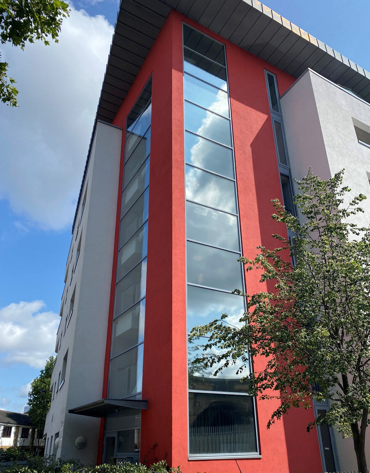 View of a modern multi-storey building featuring large glass windows with reflective window film applied to help reduce heat and glare.