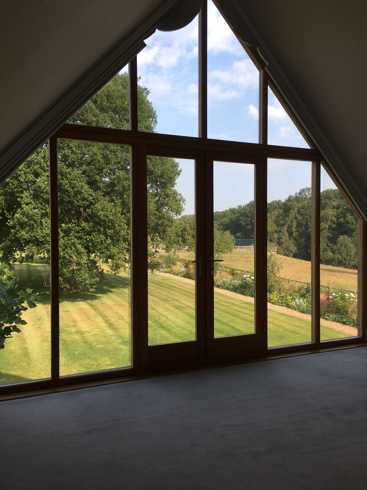 An internal view of a large expanse of glazing in a residential property. The windows overlook a large garden and there is Optiview window film applied to the glass to help reduce excess heat and cut down on glare.