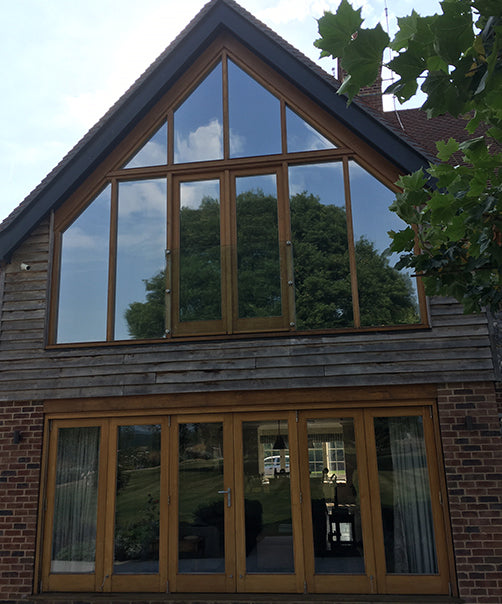 An external view of a modern home, with Optiview window film applied to windows on the second floor. 
