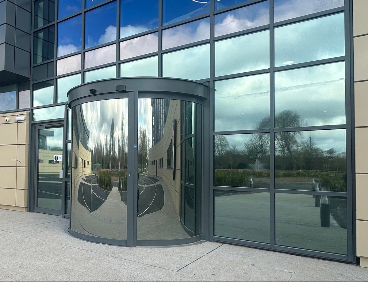 Modern building entrance with glass doors and reflective windows.