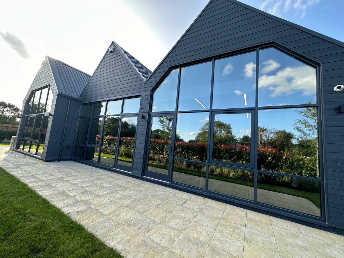 External view of a Modern building with large glass windows with solar control window film applied, reflecting trees and sky