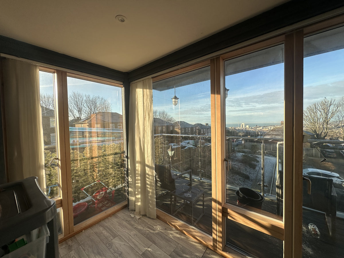 Modern room with large glass windows with solar control window film applied, offering a view of a cityscape.