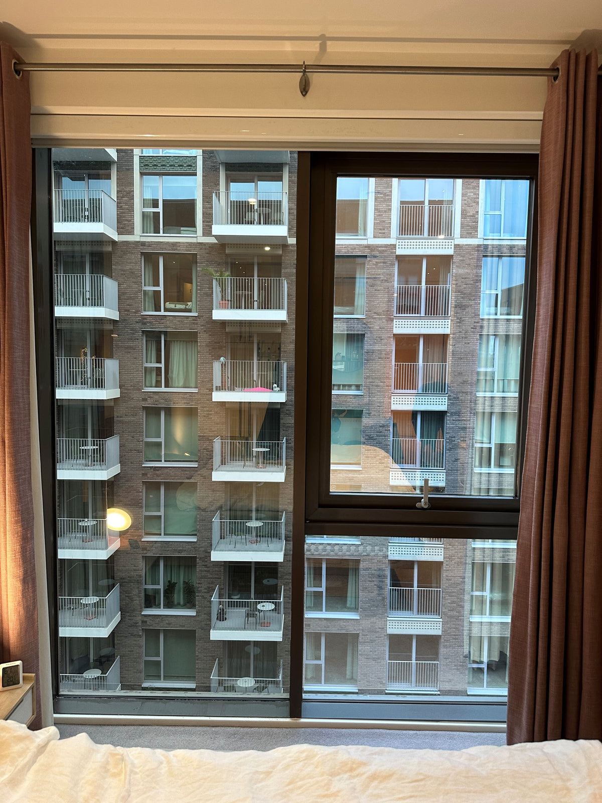View of a large floor to ceiling window, split into three panes, looking out over a block of flats. The window has heat reduction window film applied to the inside face of the glass.