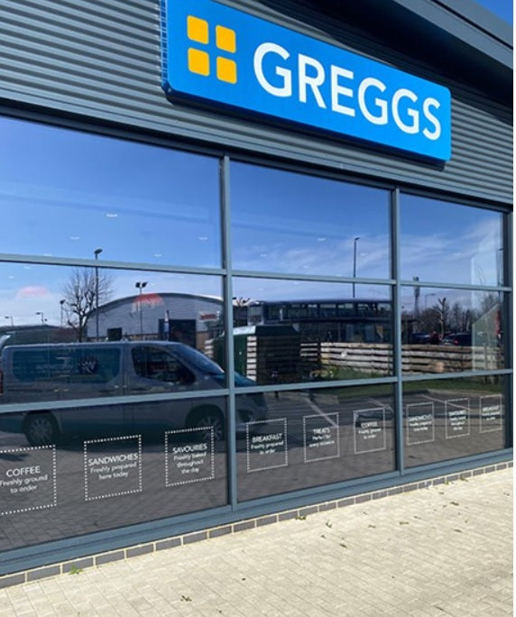 An external view of a Greggs store with a glass frontage, with solar control window film applied to the glass, delivering a stylish tinted appearance.