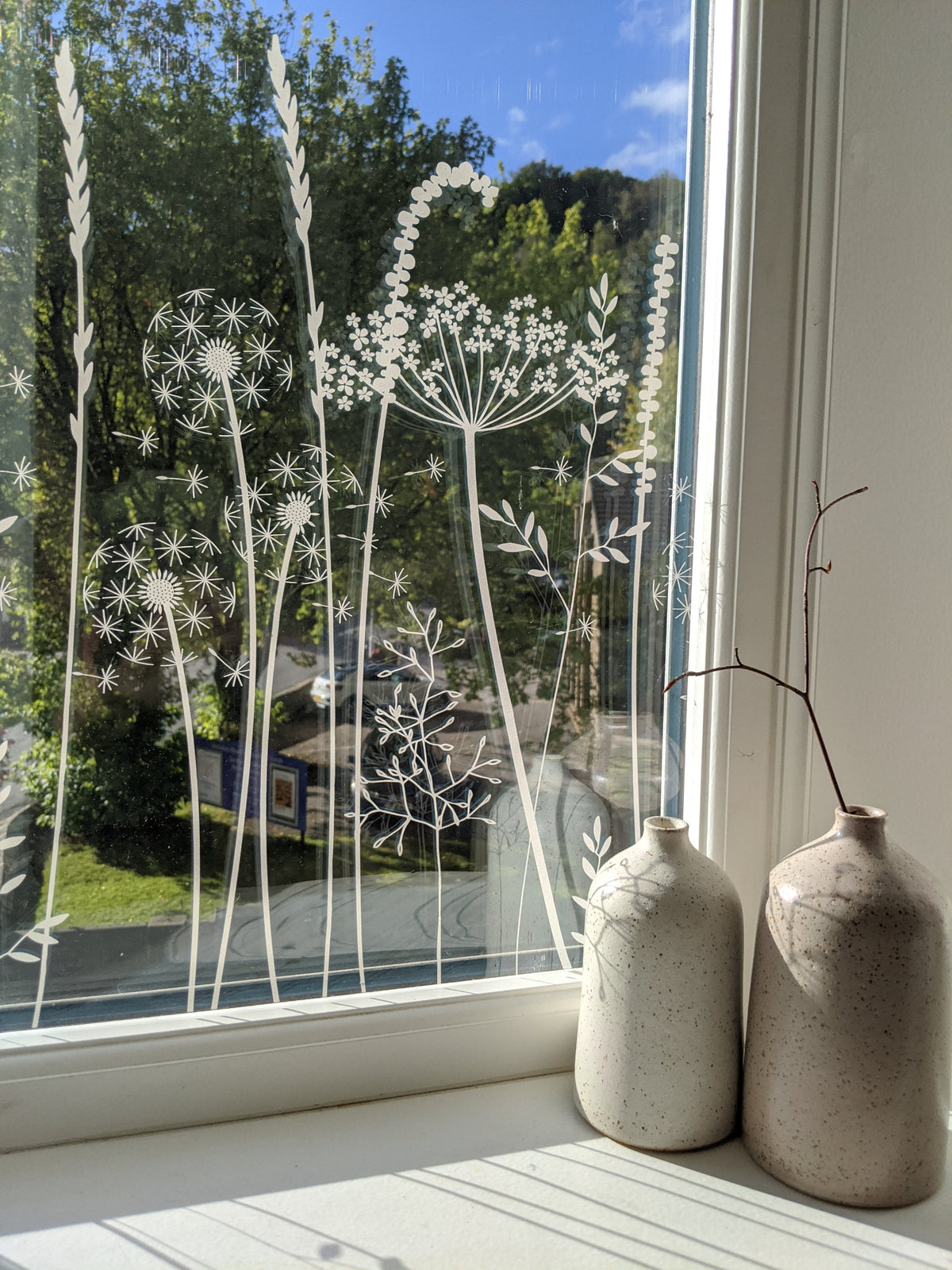 Decorative window film with floral design by Hannah Nunn on a window, with two ceramic vases on a windowsill.