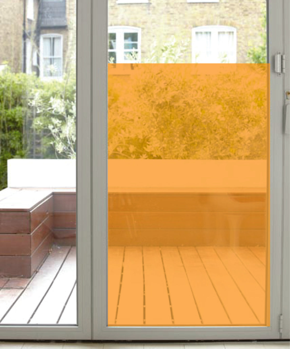 Orange coloured transparent window film applied to the lower half of a glass door, overlooking a patio area