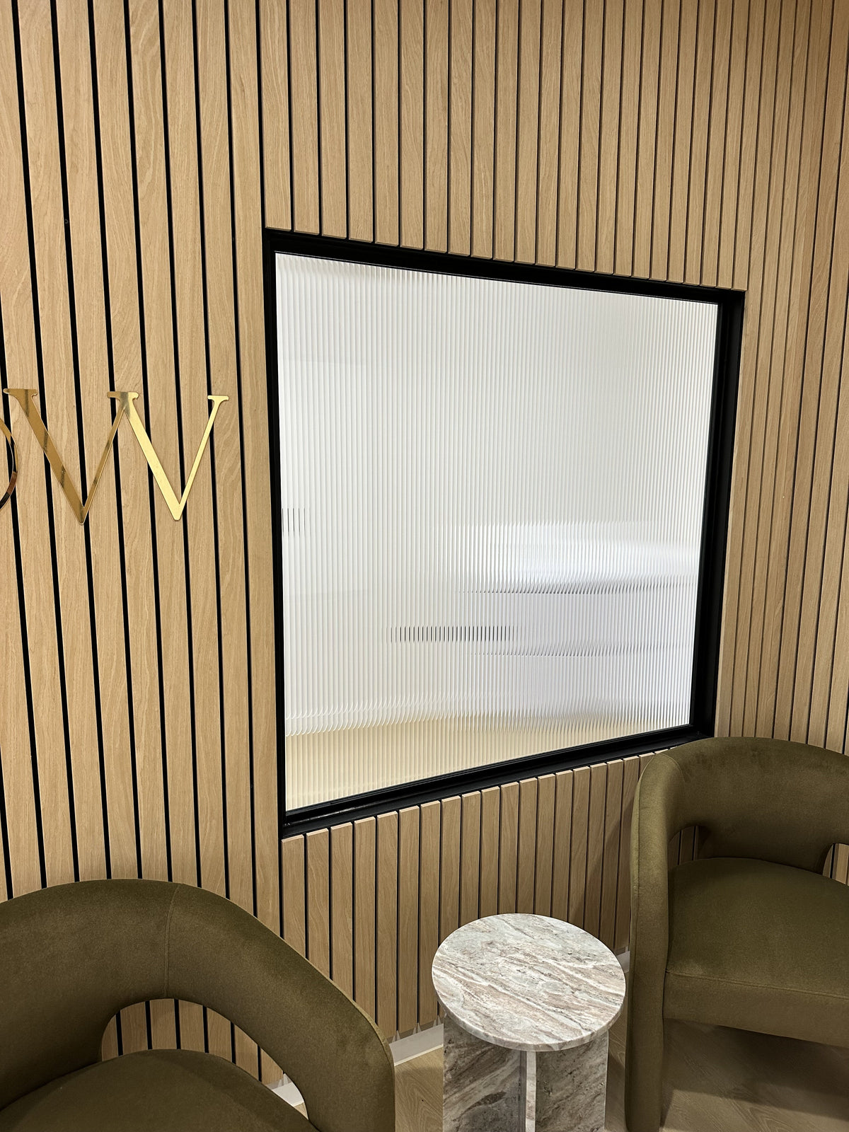 A modern waiting area with a glass vision panel that has evoke reeded window film applied for decoration.