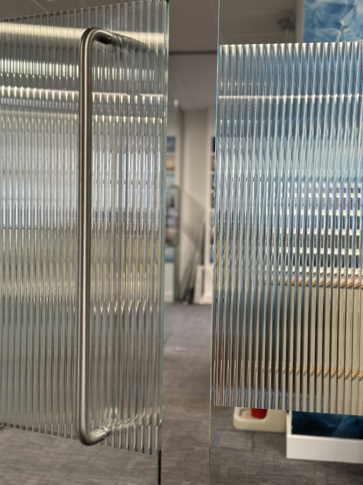 A reeded style of window film. applied to glass with a door slightly open.  This shows that the fluted film gives privacy.
